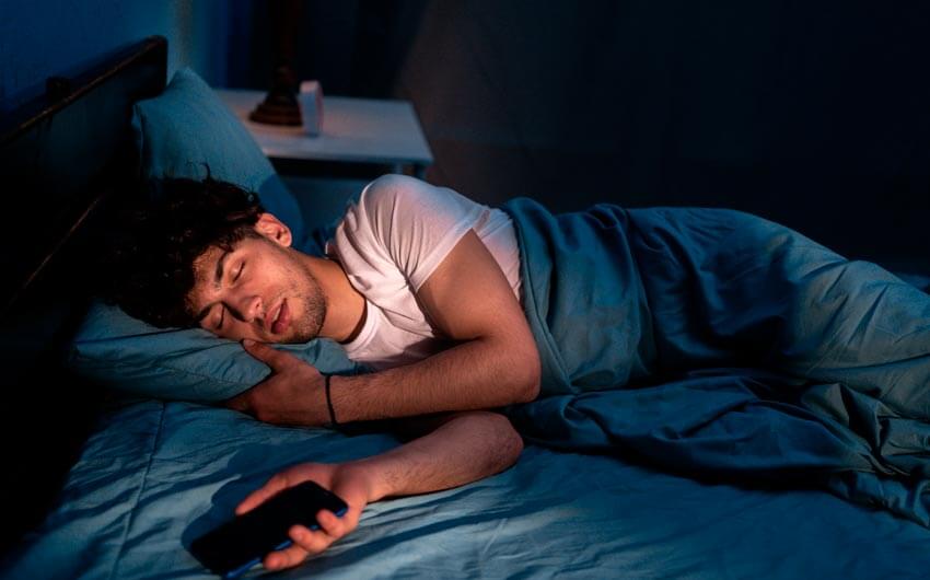Uomo che dorme con il cellulare in mano